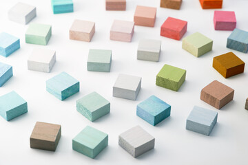 Spectrum of colorful wooden blocks scattered on white surface.  Soft pastel like colors. Background...