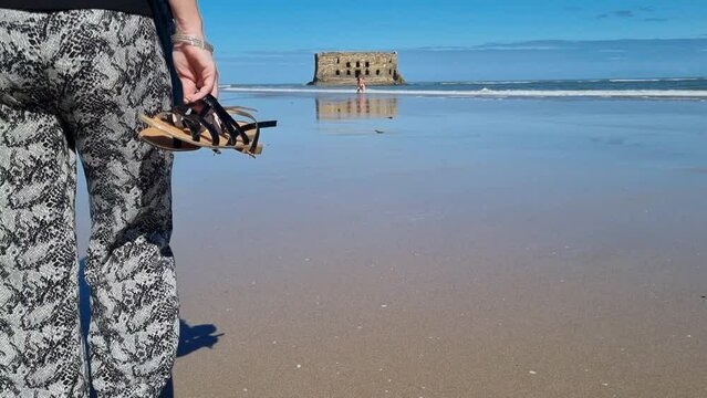 Girl with long hair walks towards the beach in Casa del mar, Tarfaya,, Marroco half body shot. Beautiful elegant girl overlooking the bay, 4K video. walk along the sandy beach.