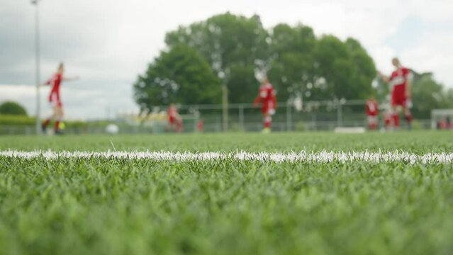 Young female soccer teenagers in red outfit passing the ball as warming up before the match