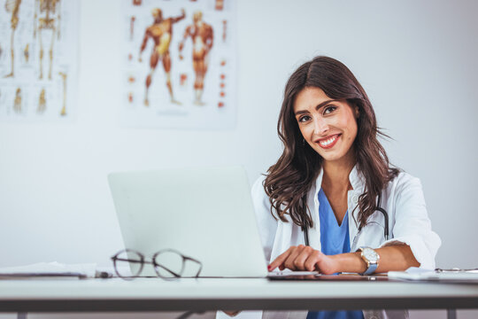 Confident female doctor sitting at office desk and smiling at camera, health care and prevention concept. Medical Doctor Indoors Portraits. Portrait of a confident doctor working at a hospital.