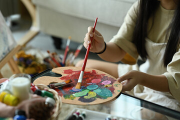 Fototapeta premium Close up with Hands of child painting with paintbrush and palette watercolor paints palette. Painting Master Class.