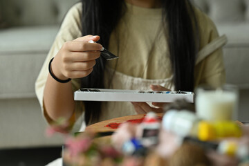 The front close up with hands is catching the colorful acrylic watercolor set, education and art object.