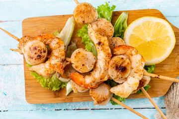 Seafood skewers on a wooden board, top view. Shrimp and scallop skewers