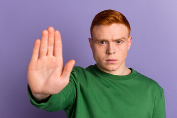 Photo of young man show arm no stop ban block forbidden rejection symbol isolated over violet color background