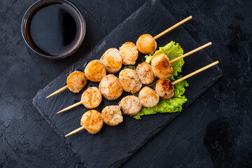 Grilled scallops on skewers top view. Dark table.