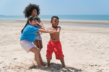 Happy kids play tug-of-war on the beach