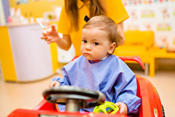 Baby's first haircut. Cute little boy at the professional children's hairdresser.