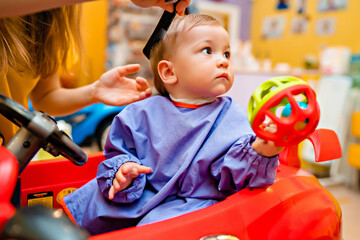 Baby's first haircut. Cute little boy at the professional children's hairdresser.