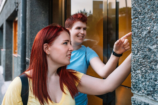 two young, urban woman ringing the doorbell of a block of buildings in a big city. young girls in the city sharing free time while gossiping. concept of friendship and companionship.