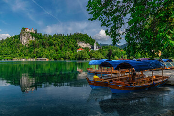 Traditional Pletna boat on the Bled lake. A boat that transports tourists to the island where the church Assumption of Maria .In the background is the famous old castle on the cliff. Bled, Slovenia