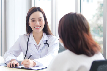 Fototapeta premium Asian professional doctor woman who wears medical coat talks with woman patient to suggest treatment guideline and healthcare concept in office of hospital.