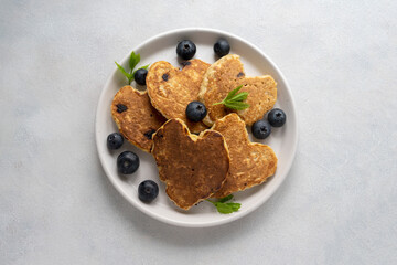 Pancakesheart shaped with fresh blueberries, Morning breakfast, delicious vegan pancakes. Bright background.