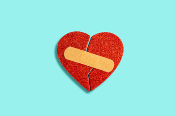 Broken habstract heart with medical patch on blue background