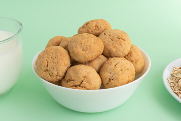Homemade oatmeal cookies on a white plate on a green background. The concept of healthy eating and cooking cookies. High-quality photo