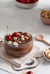 Avocado chocolate pudding, glass dessert on a light background decorated with cherries.