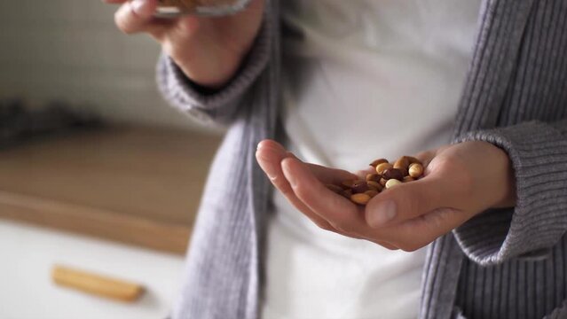 Breakfast concept girl holding peanut nuts stands in the kitchen nutritious diet. Healthy food high-calorie tomorrow, a young girl eats fresh peanuts not fried
