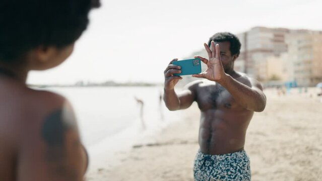 African american man and woman couple wearing swimsuit make photo by smartphone at seaside