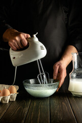 Professional chef uses a hand-held electric mixer to prepare a delicious breakfast or lunch with eggs and milk. Menu idea for a restaurant or hotel