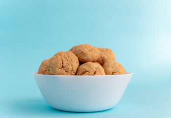 Homemade oatmeal cookies on a white plate on a blue background. The concept of healthy eating and cooking cookies. High-quality photo