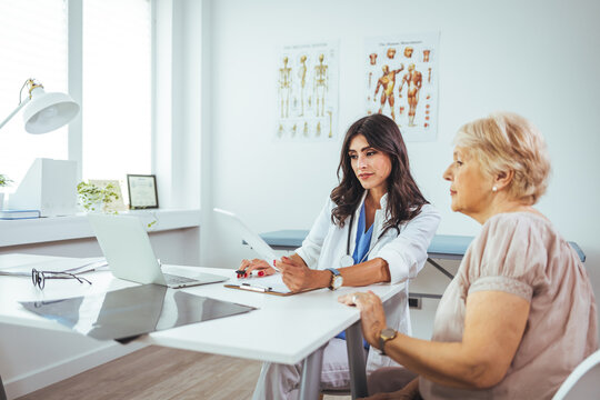 Female doctor explaining diagnosis to her patient. A smiling mid adult female doctor listens as a female patient discusses her health. Caring doctor listens to patient