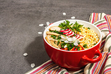 Asian noodles with chicken, vegetables, and herbs in a red bowl. Traditional Japanese soup