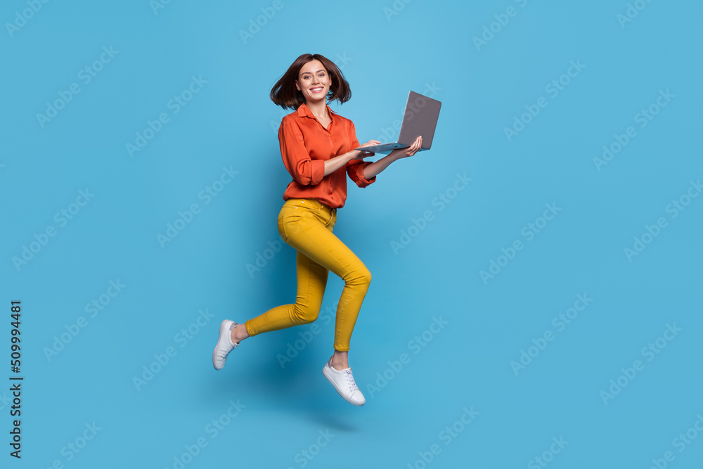 Poster Full length body size view of attractive cheery skilled trendy girl jumping using laptop isolated over bright blue color background