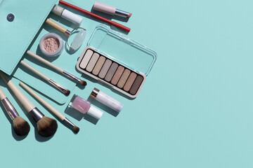 Summer  make-up products flat lay on blue marine turquoise bakground with copy space, beach holiday beauty items coming out of clutch bag