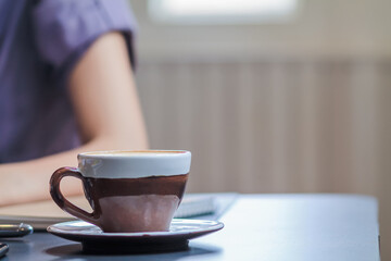 Ceramic coffee cups filled with hot coffee are placed on a table in a coffee shop after a businesswoman orders hot coffee to relax during her lunch break. Copy space is available for inserting text