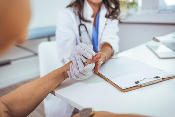 Cropped shot of an unrecognizable female nurse comforting a patient in the hospital. Doctor woman holding hand for reassuring her female patient. Offering care and comfort when in need