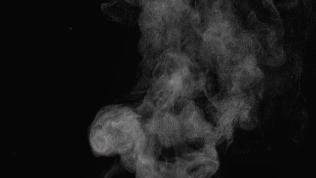 Water vapor. White jet of steam ascending and floats in air on black background. Micro drops of hot water are sprayed in air close up. Clouds of thick mist swirl. Smoke fog. Gaseous state.