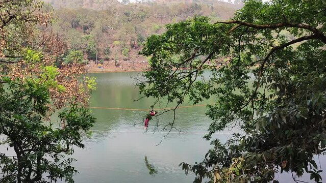 Man moving on zip line by lake