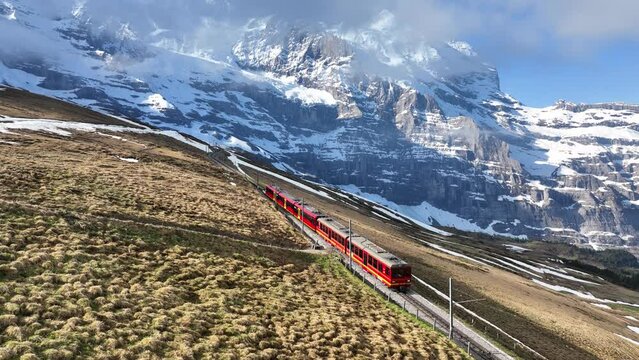 tourist alpine train moving in Swiss alps, mountain railway in Switzerland, Swiss tourism and Swiss transport infrastructure concept