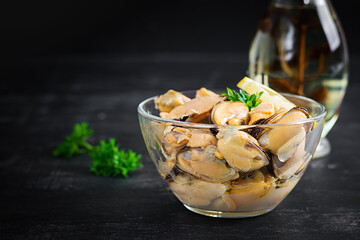 Delicious mussel meat with lemon and fresh parsley on a dark background.