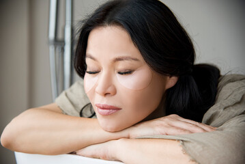 portrait of  asian beautiful woman with transparent patch under eye relaxing with close eyes in spa salon
