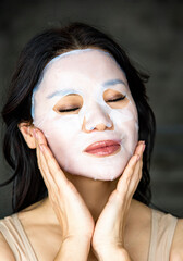 Sensual photo of beautiful young asian woman with with eyes closed, applying cotton facial...