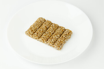 Sweet brittle sticks of sunflower seeds in sugar glaze on a white plate.