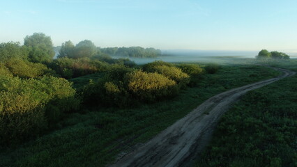Obraz premium Bird's eye view of the mist over the river and meadows on an early summer morning