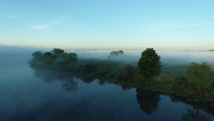 Bird's eye view of the mist over the river and meadows on an early summer morning