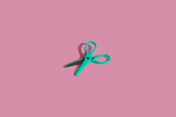 Flat lay composition with school green scissors supplies on pink pastel background. Vivid color minimal overhead shot with copy space. Back to school concept. Top view with sharp shadows.