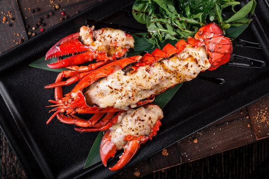grilled lobster lobster meat on black plate with arugula leaves
