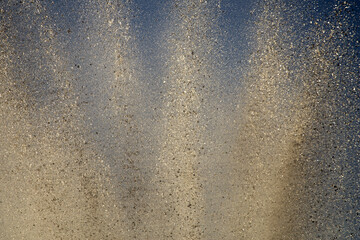 Bright splashes of the water fountain against the blue sky. Abstract color composition in sunshine backlight.