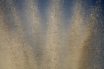 Bright splashes of the water fountain against the blue sky. Abstract color composition in sunshine backlight.