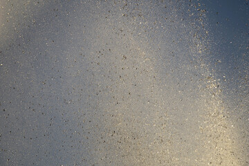 Bright splashes of the water fountain against the blue sky. Abstract color composition in sunshine backlight.