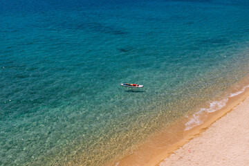 Aerial view of woman  lies down on a paddle board and enjoys relaxation