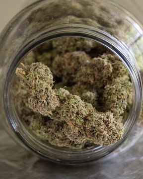 Cannabis buds in glass jars with a neutral light background.