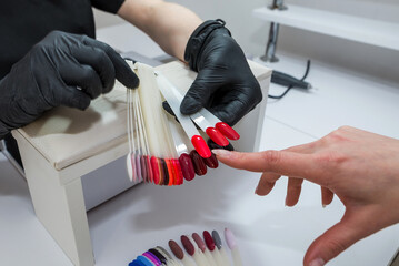 Choice of nail color. A young girl chooses the color of her nails in a beauty salon. Beauty and...