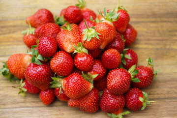 Heap of fresh strawberries on wooden cutting board with natural background.