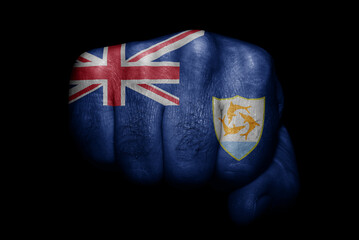Flag of Anguilla painted on strong fist on black background - obrazy, fototapety, plakaty