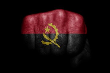 Flag of Angola painted on strong fist on black background