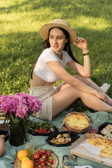 young girl with a guy on a picnic on vacation. green litter with food and flowers sunny bright day